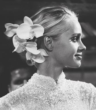 Black and white profile of a bride wearing white orchids in her hair instead of a veil
