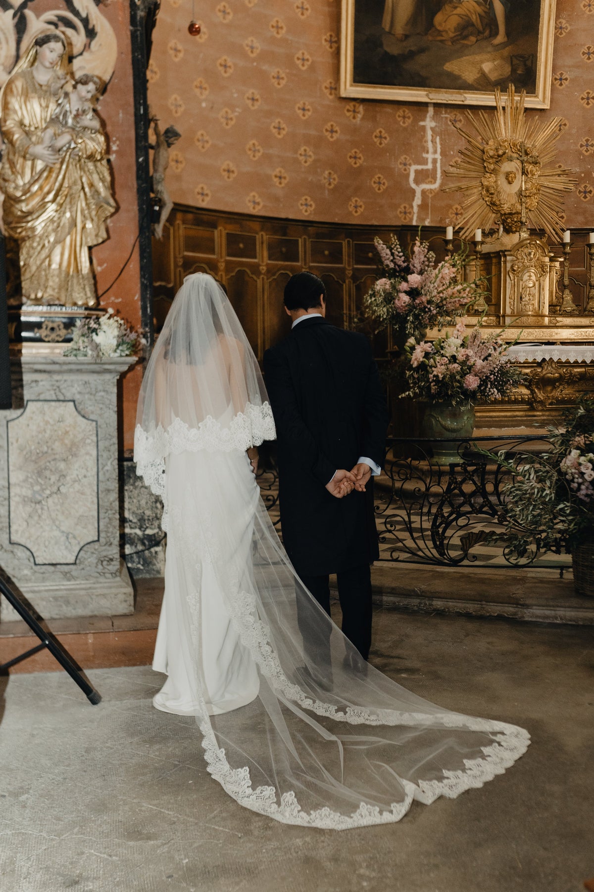 Traditional ace wedding veil worn by a Catholic bride in a church aisle
