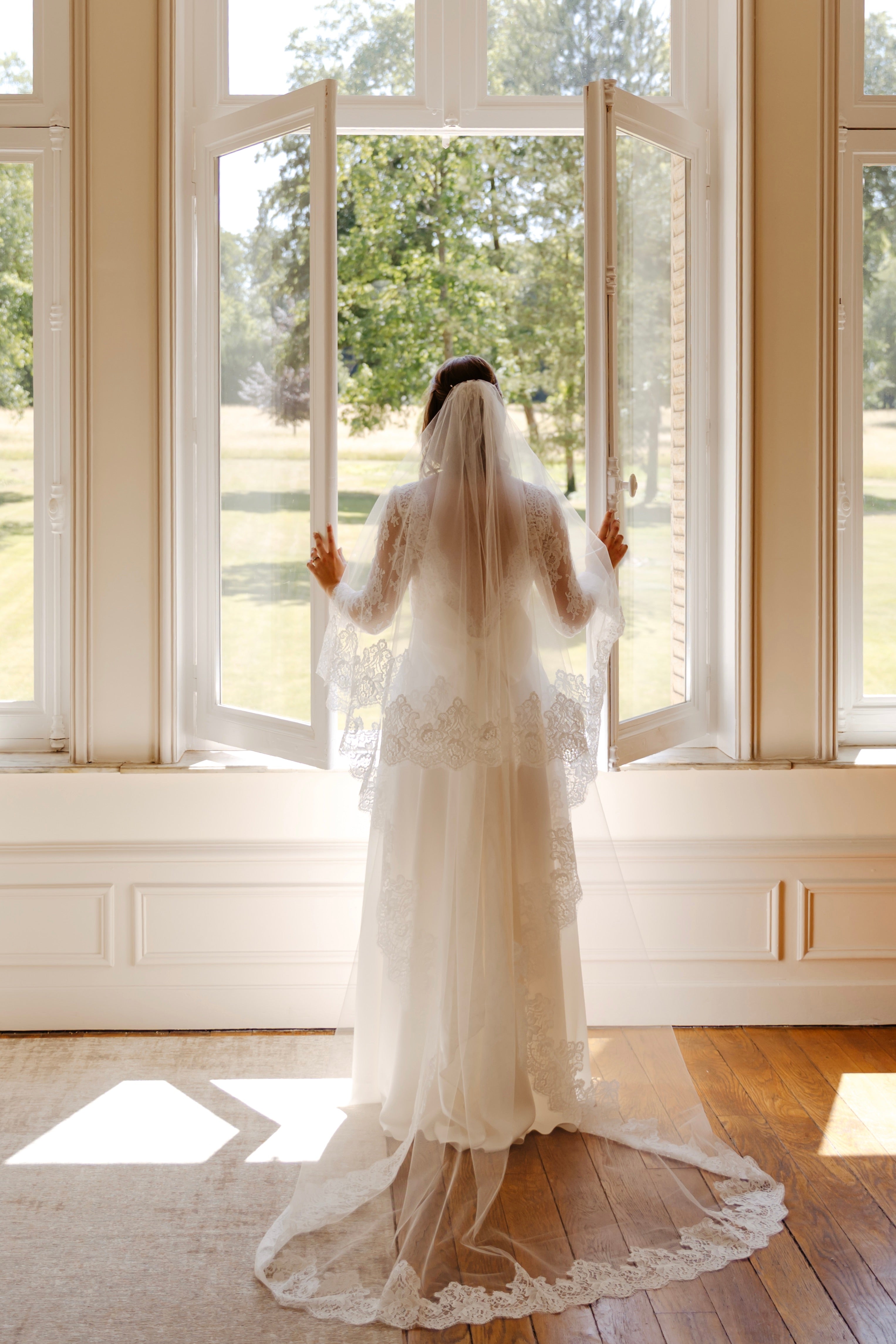 Long cathedral wedding veil in fine tulle and Calais lace, framing the shoulders with a clean, architectural line