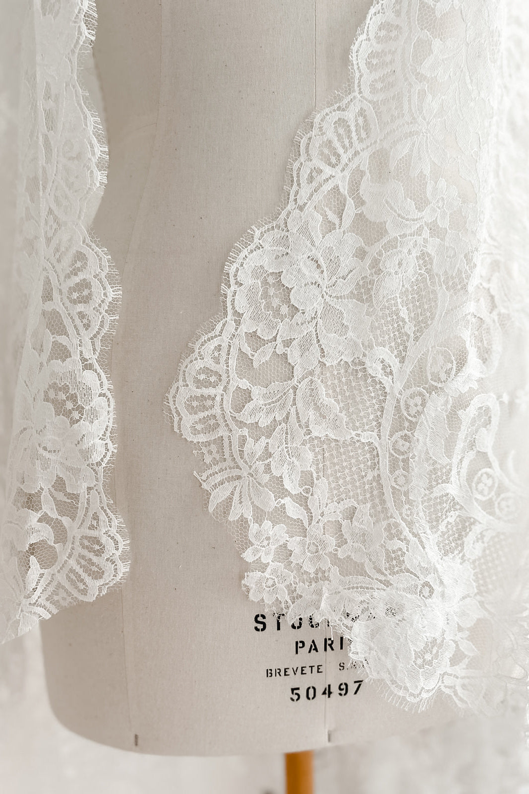 Ivory Calais lace mantilla draped over a Stockman dress form in our Paris atelier