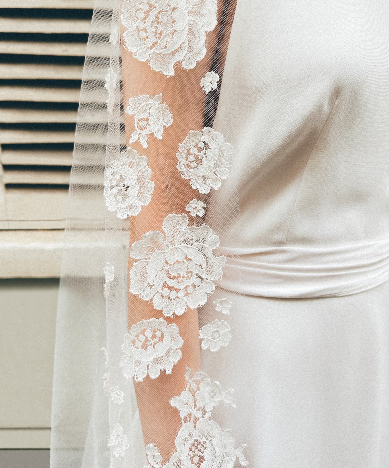 Close-up of intricate lace details on a bridal veil, worn by a bride, showcasing elegant craftsmanship and wedding fashion.
