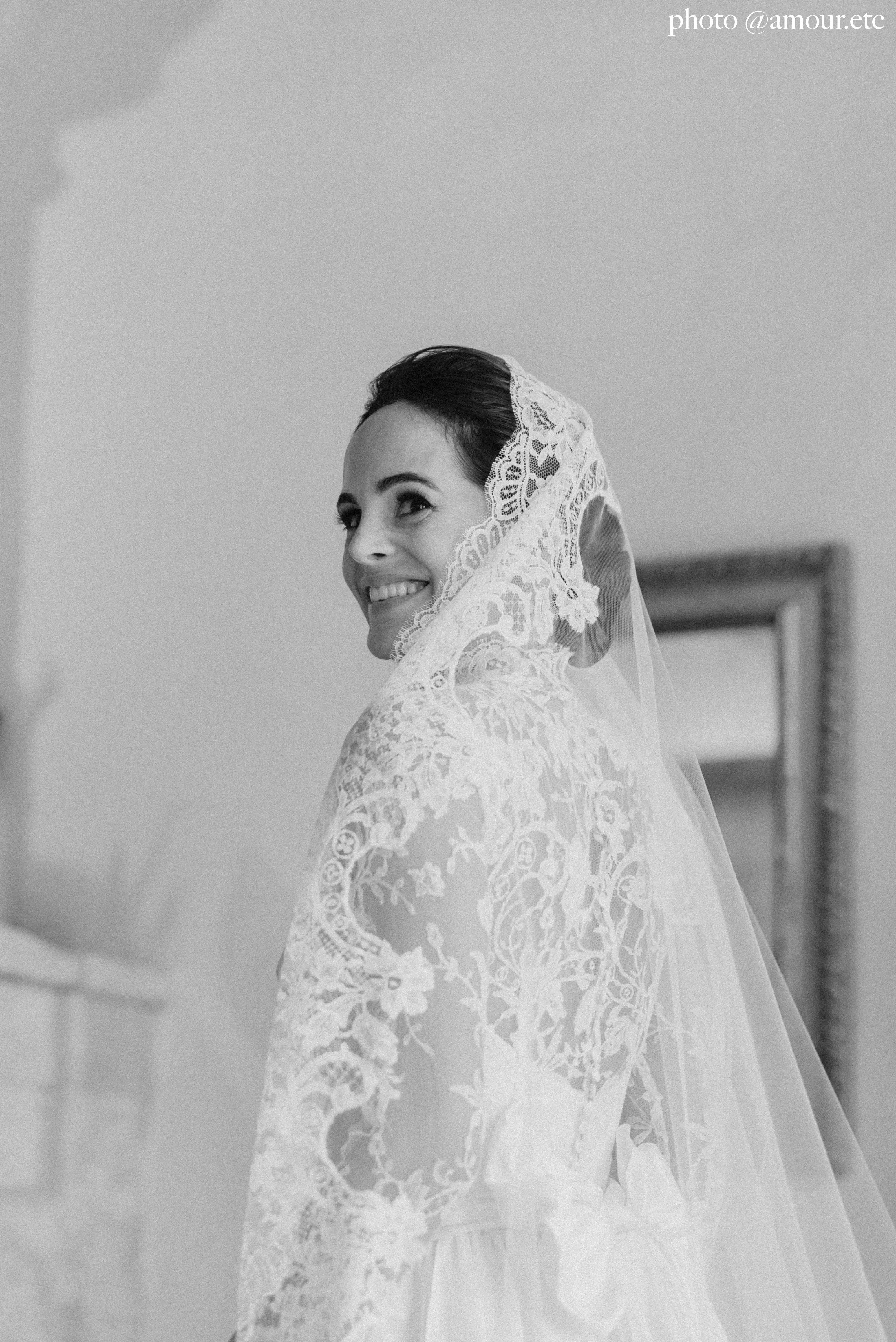 A bride wearing a lace cathedral wedding veil on her wedding day. Her bridal veil is worn as a mantilla in her hair.