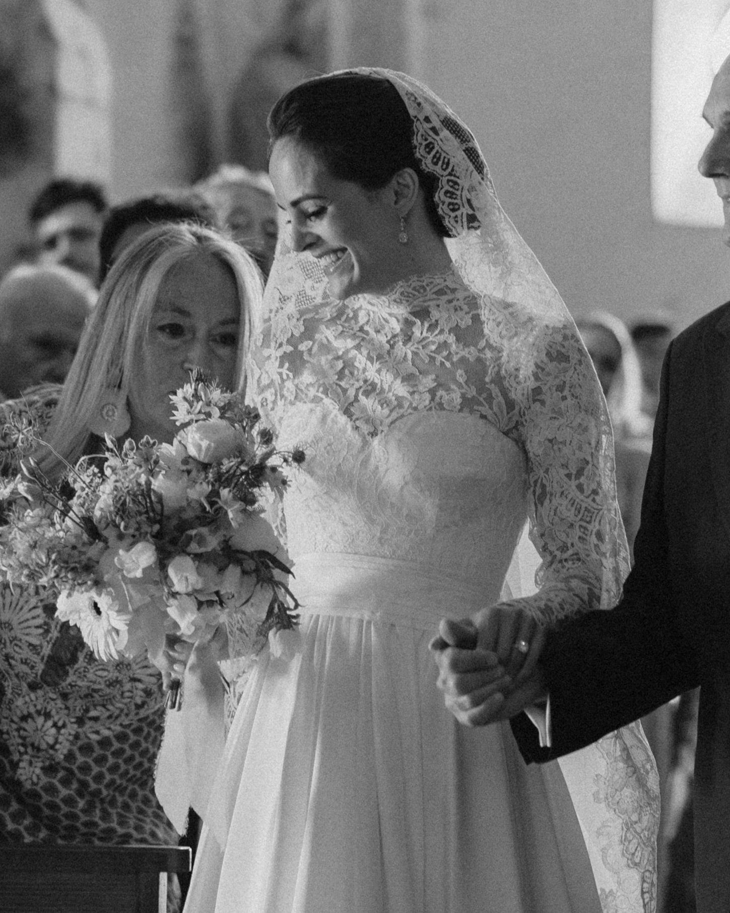 Bride walks down the aisle with a mantilla wedding veil in her hair.