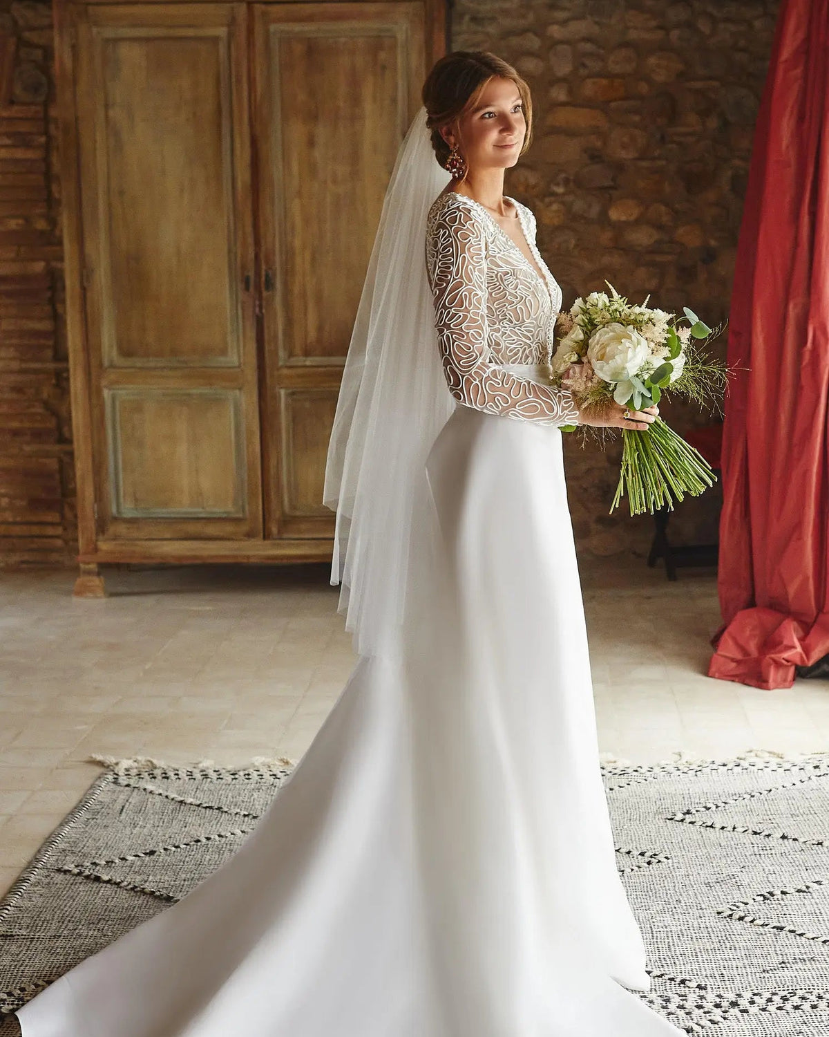 Bride in a lace-sleeved gown wearing the Pour Toujours fingertip tulle wedding veil