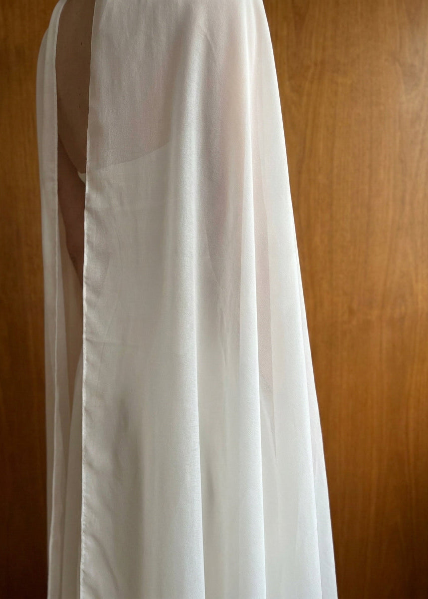 Close-up over-the-shoulder view of a silk chiffon bridal cape, soft folds of sheer fabric in natural light