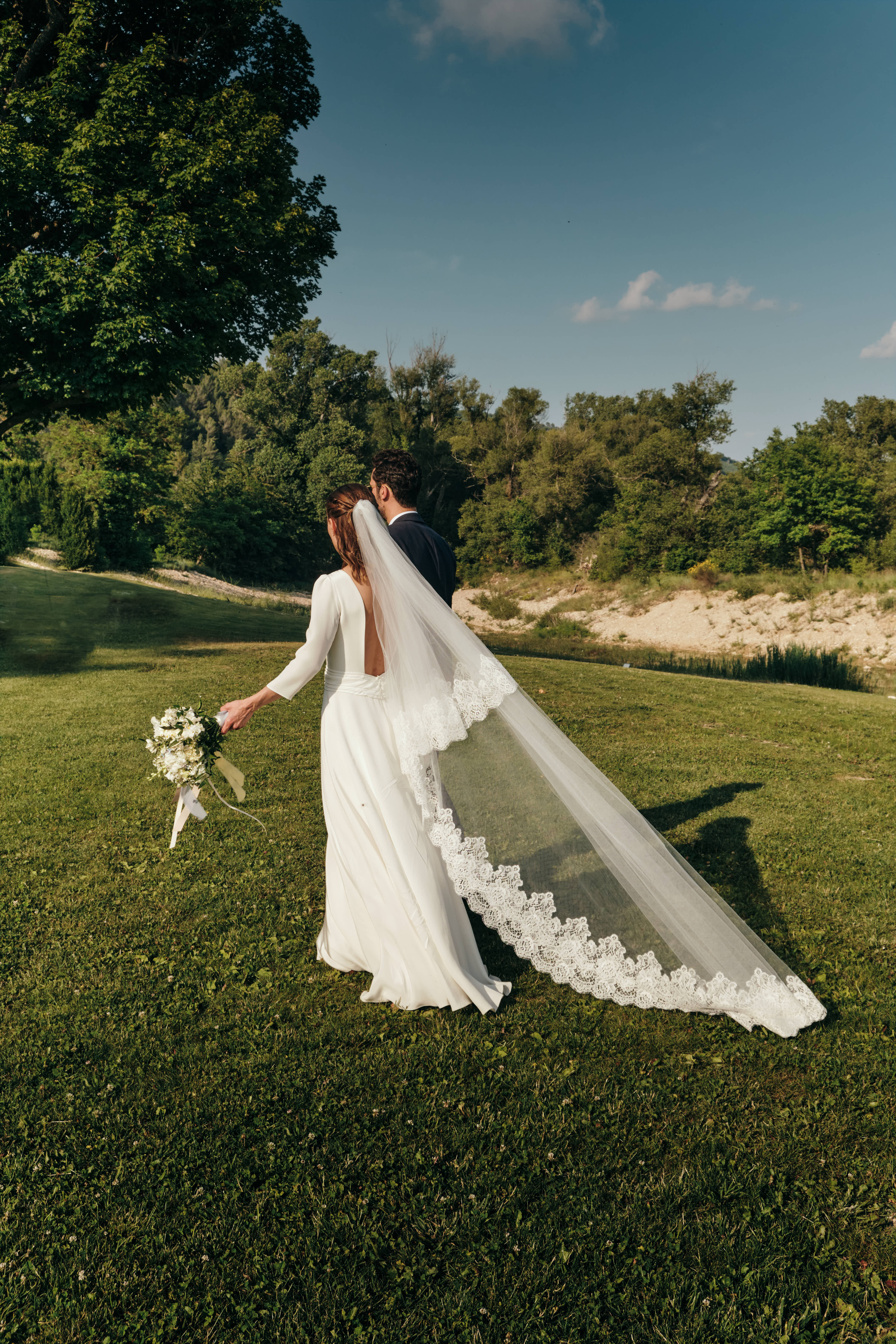 Bride wearing a lace wedding veil that is flowing in the wind