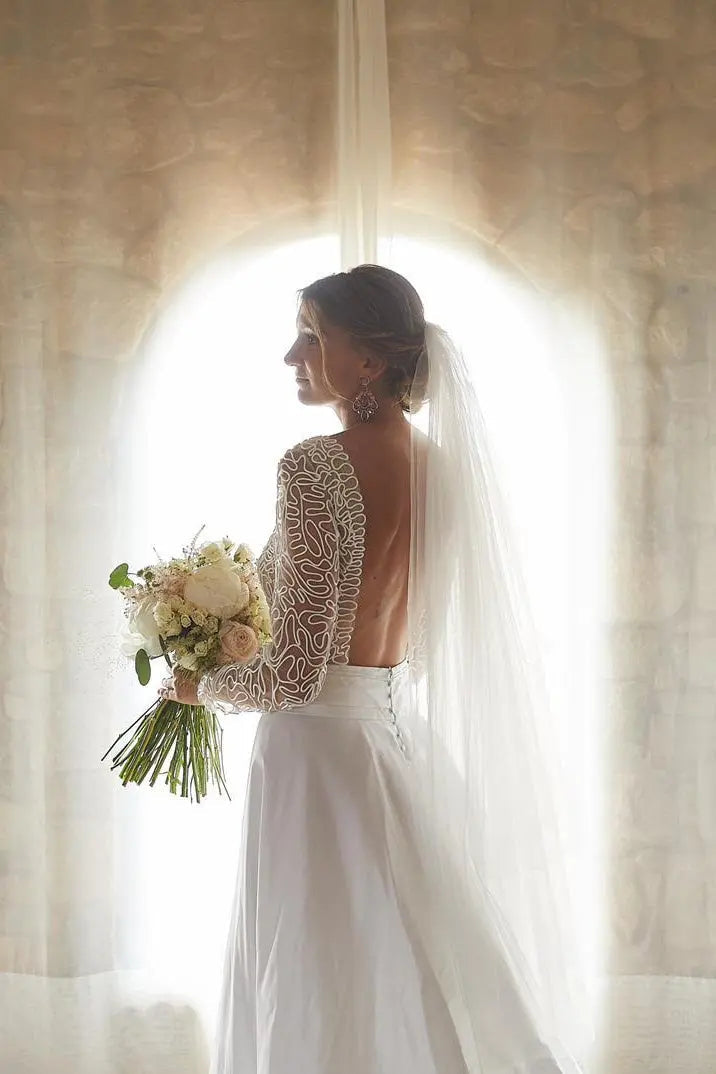 Bride wearing a soft tulle short wedding veil with loose waves and a minimalist gown