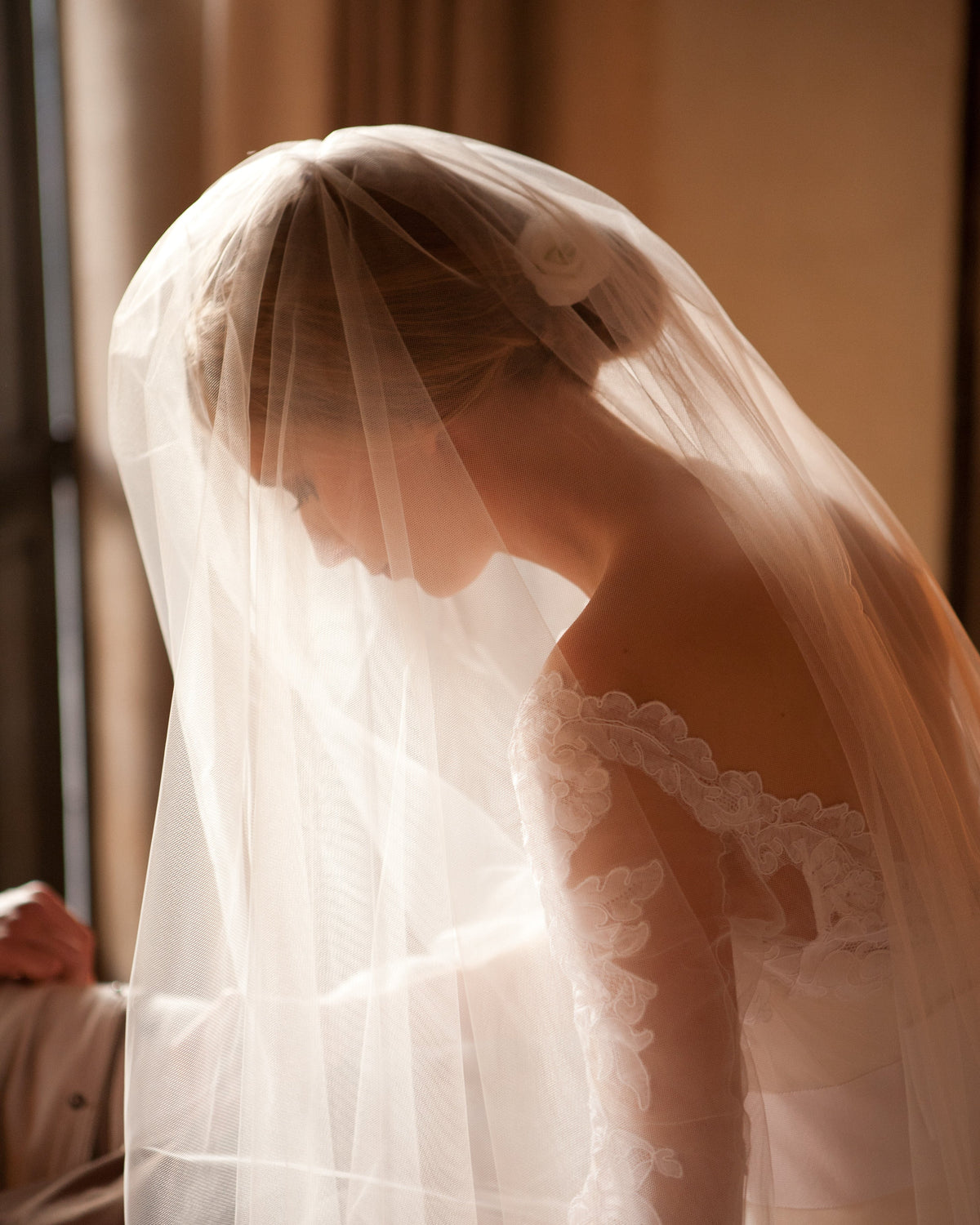 Bride wearing a bridal veil in tulle with blusher over her face
