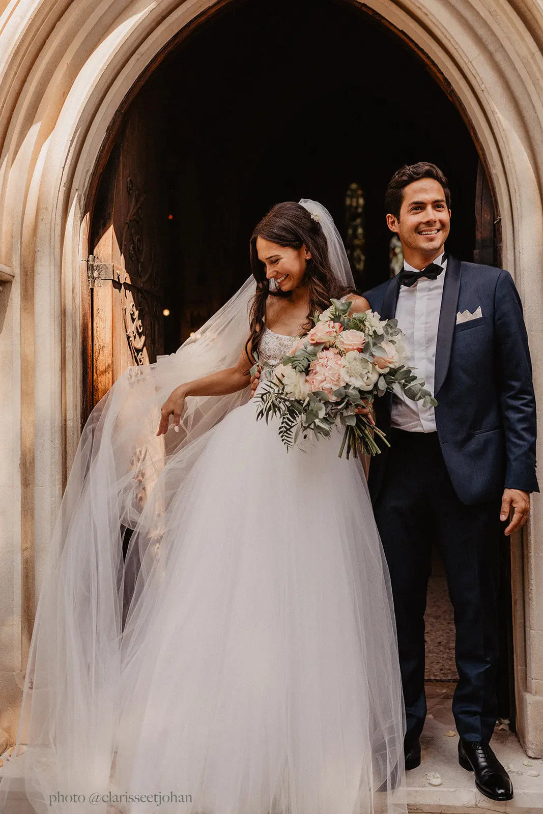 Long tulle bridal veil fluttering in the breeze during a ceremony inside a church.