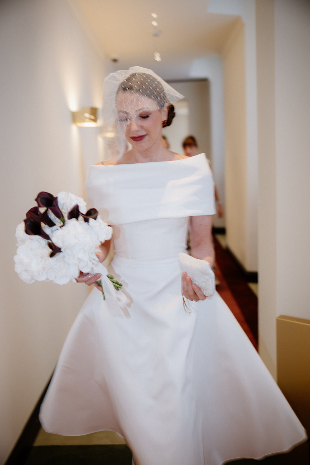 Wedding portrait of a bride in a 1950s-style birdcage veil and tea-length dress