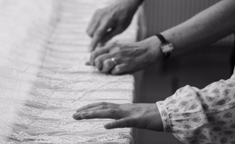 Two hands working on a lace fabric, carefully adjusting the folds, illustrating a craft process of sewing or creating clothes.