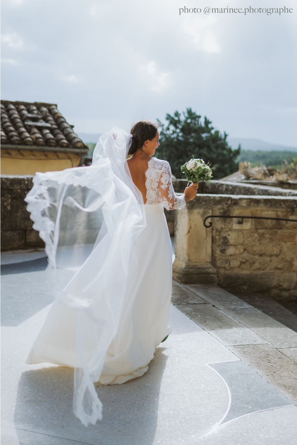 Romantic lace veil flowing behind bride during outdoor ceremony