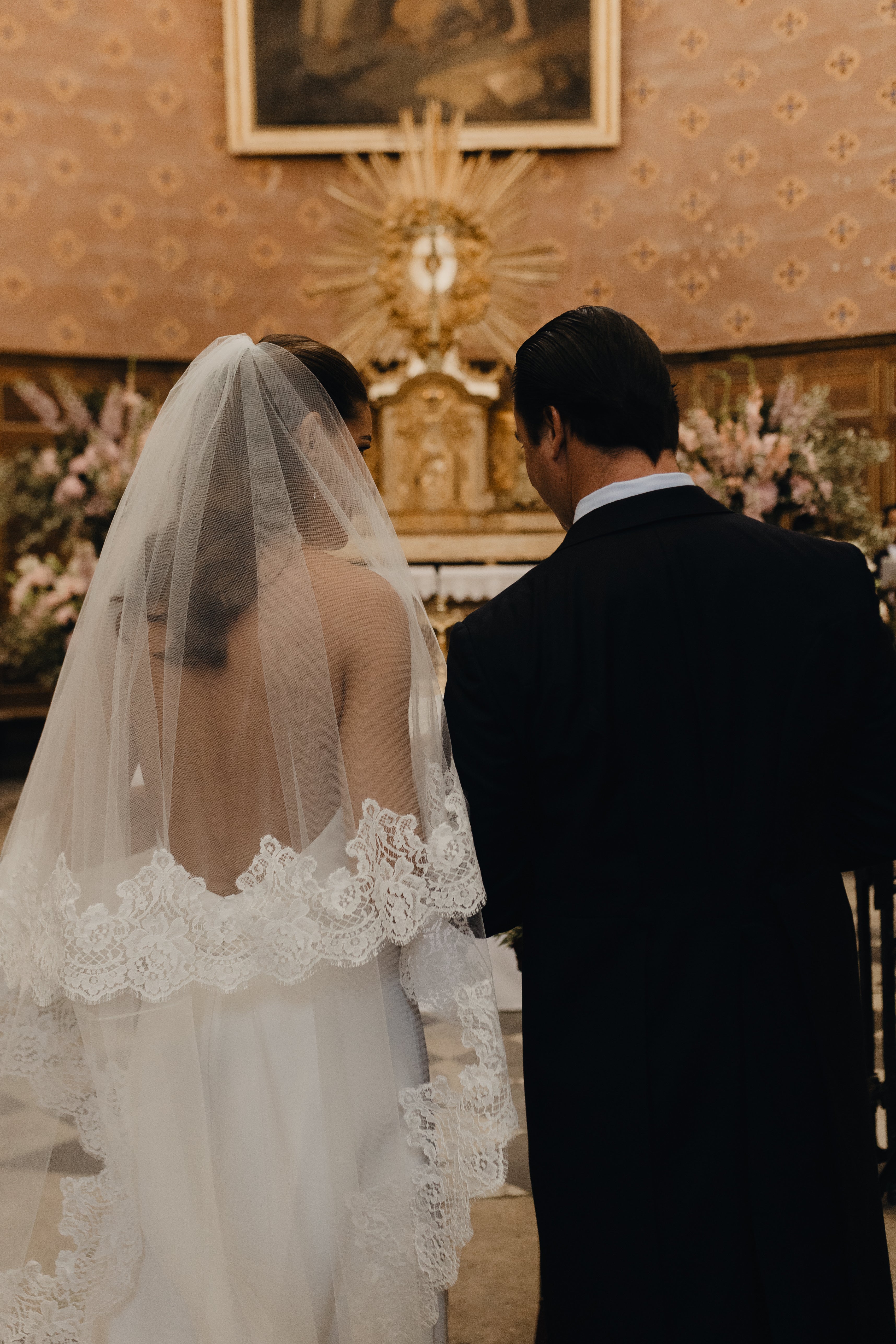 View from behind of the Mon Amour lace veil during a church wedding ceremony