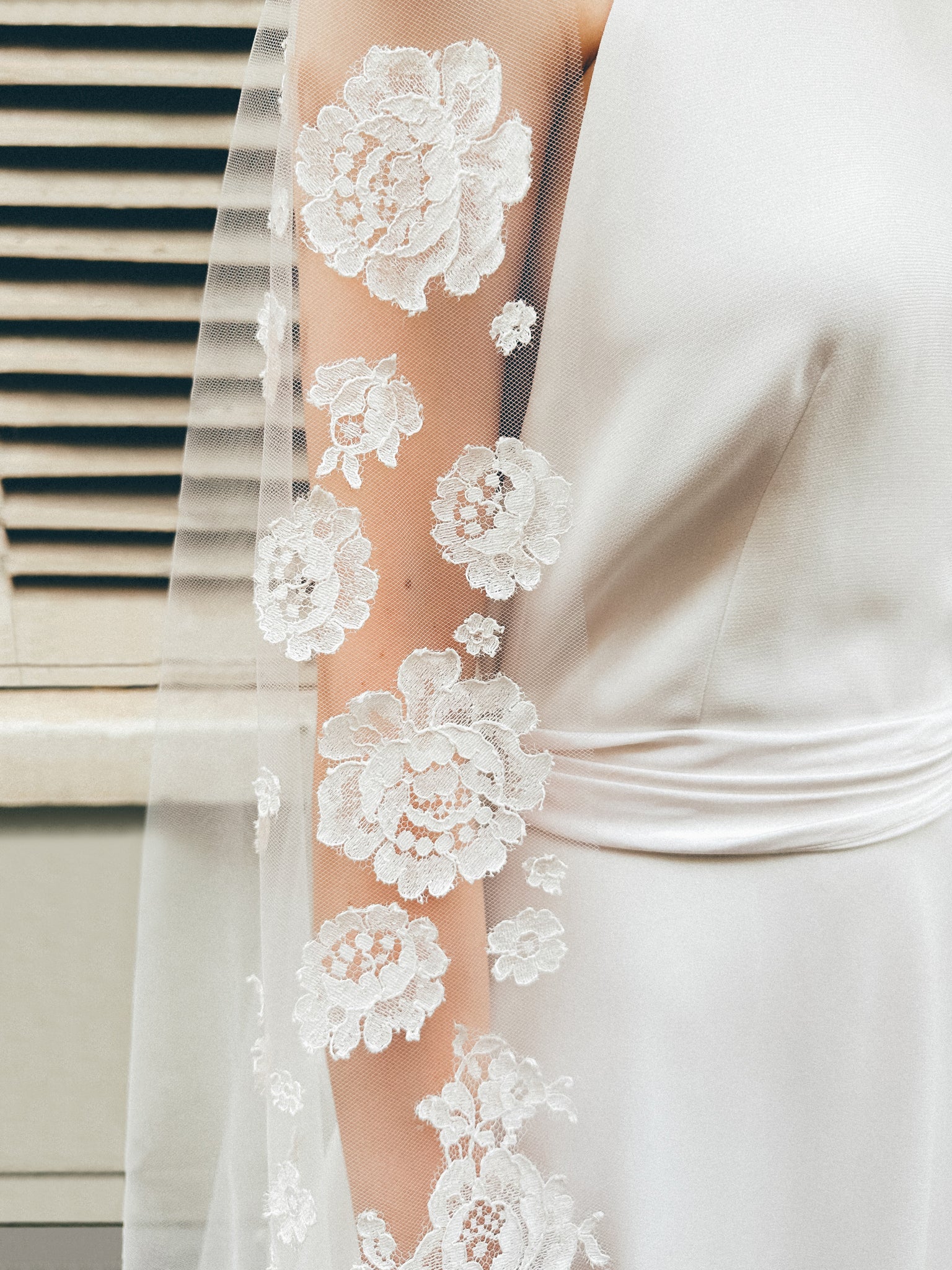 Close-up of intricate lace details on a bridal veil, worn by a bride, showcasing elegant craftsmanship and wedding fashion.