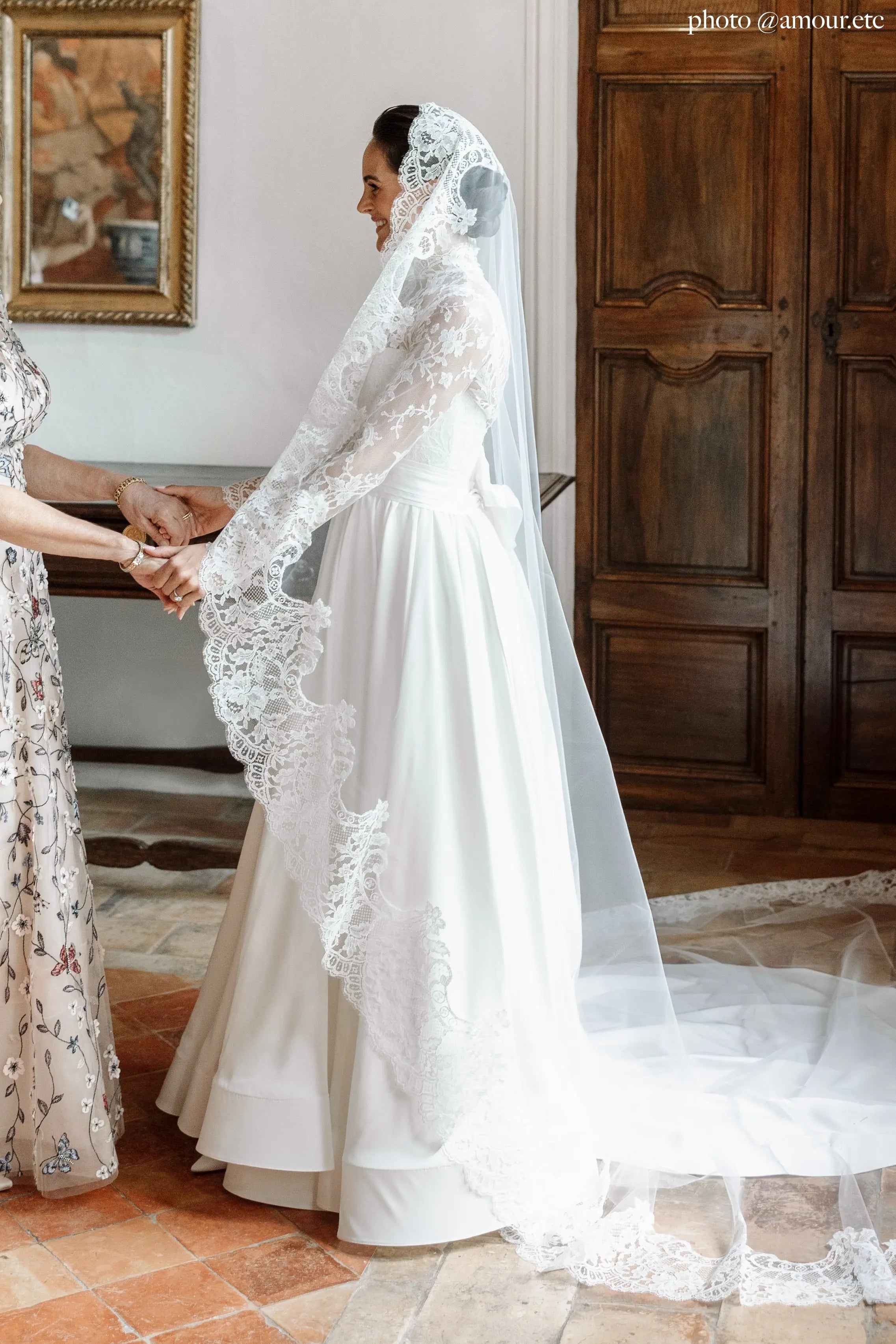 Long lace wedding veil worn as a mantilla in tulle, creating a dreamy silhouette.