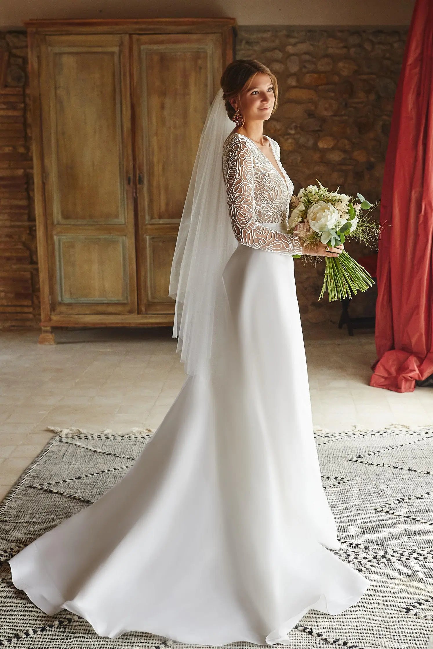 Bride wearing a long tulle veil flowing gently behind her.