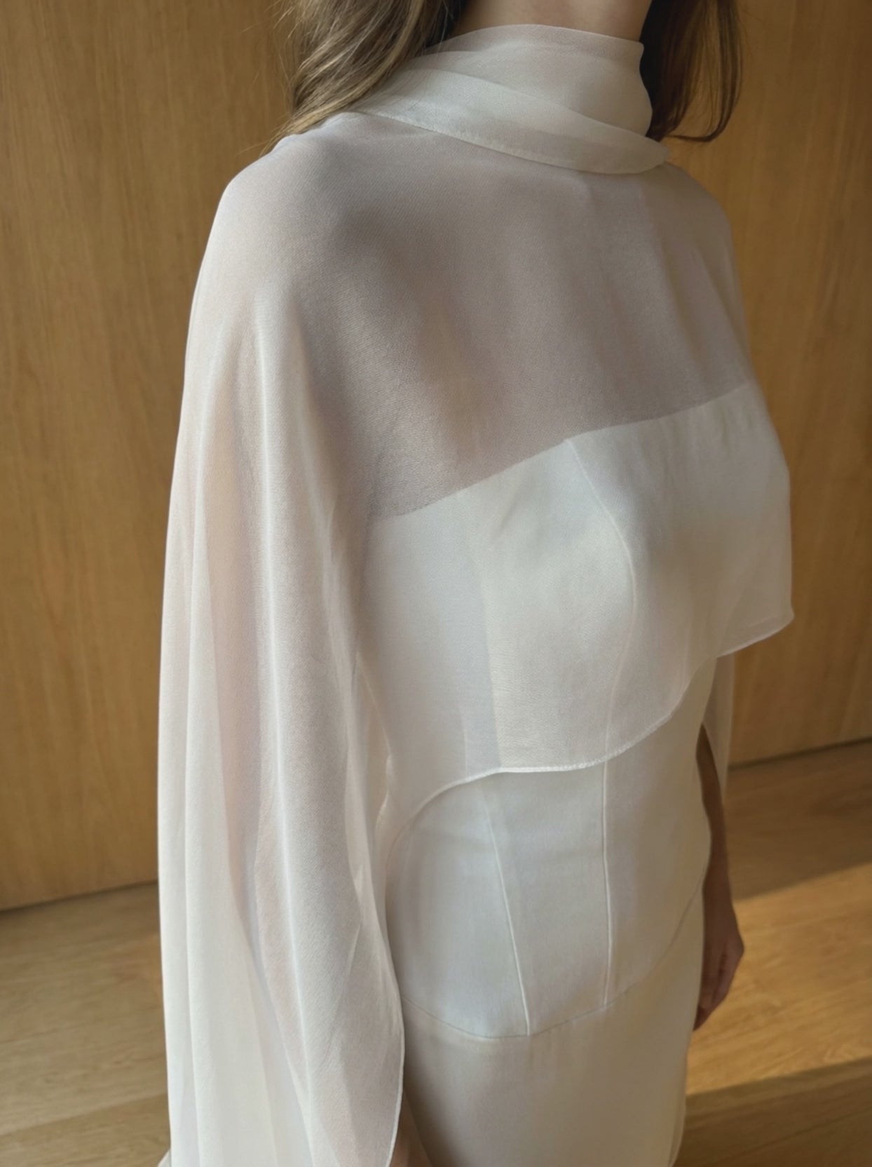 Silk chiffon bridal cape in motion, sheer fabric moving over a corseted wedding gown as the bride turns