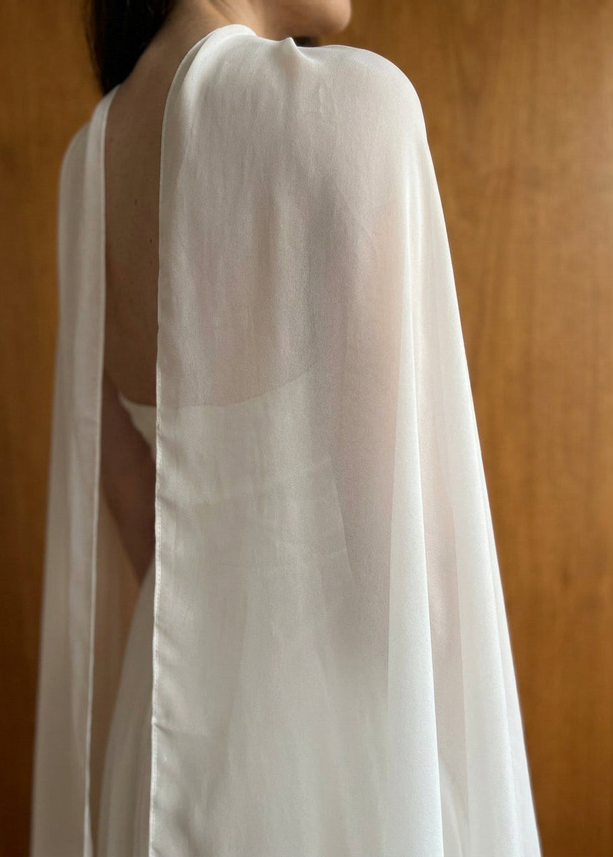 Side view of sheer silk chiffon draping along an open-back wedding gown, natural white silk cape