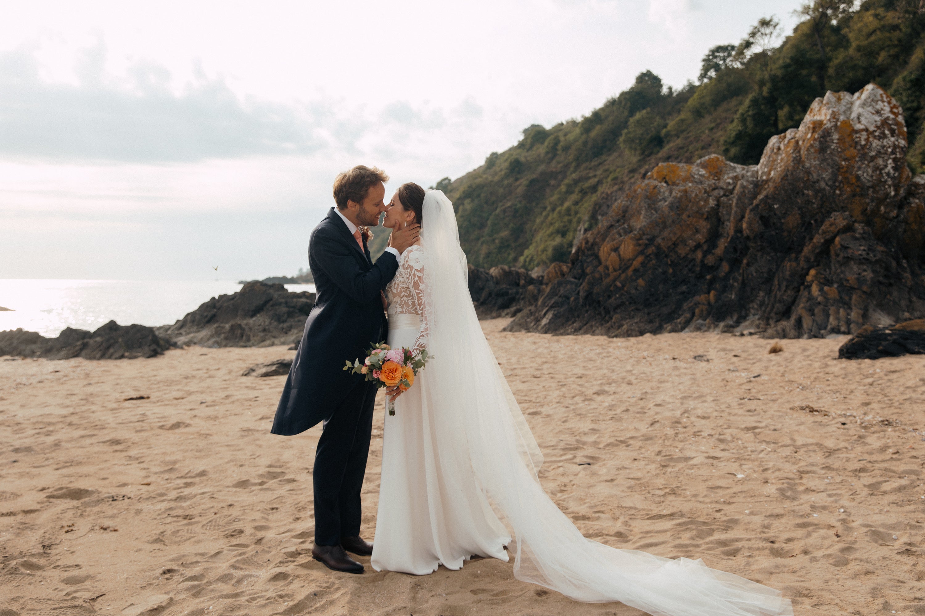 How to wear a long wedding veil – side view of a bride on a beach with a cathedral veil flowing behind her