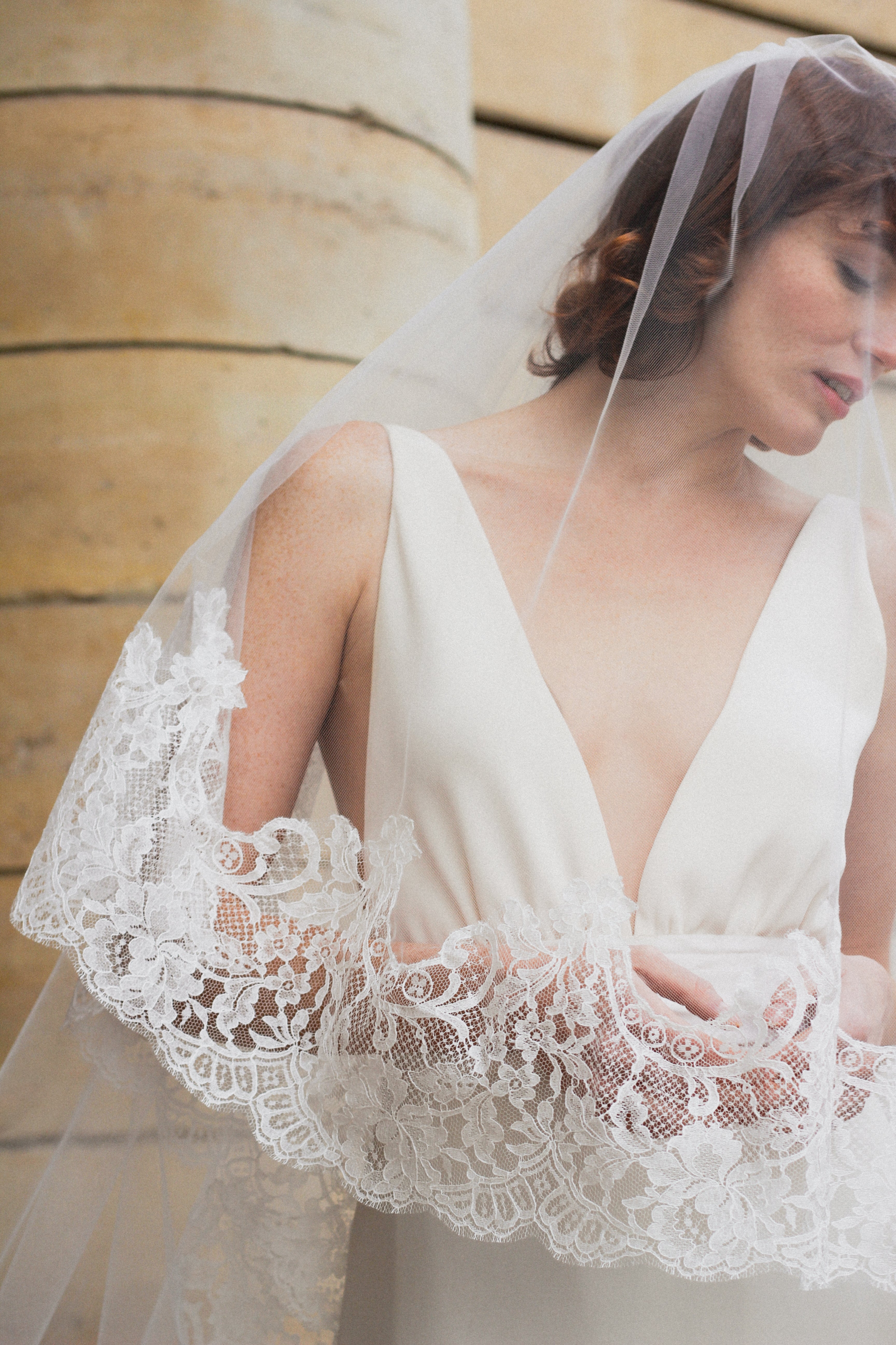 Young bride wearing an ivory cathedral bridal veil in fine tulle with elegant embroidery.