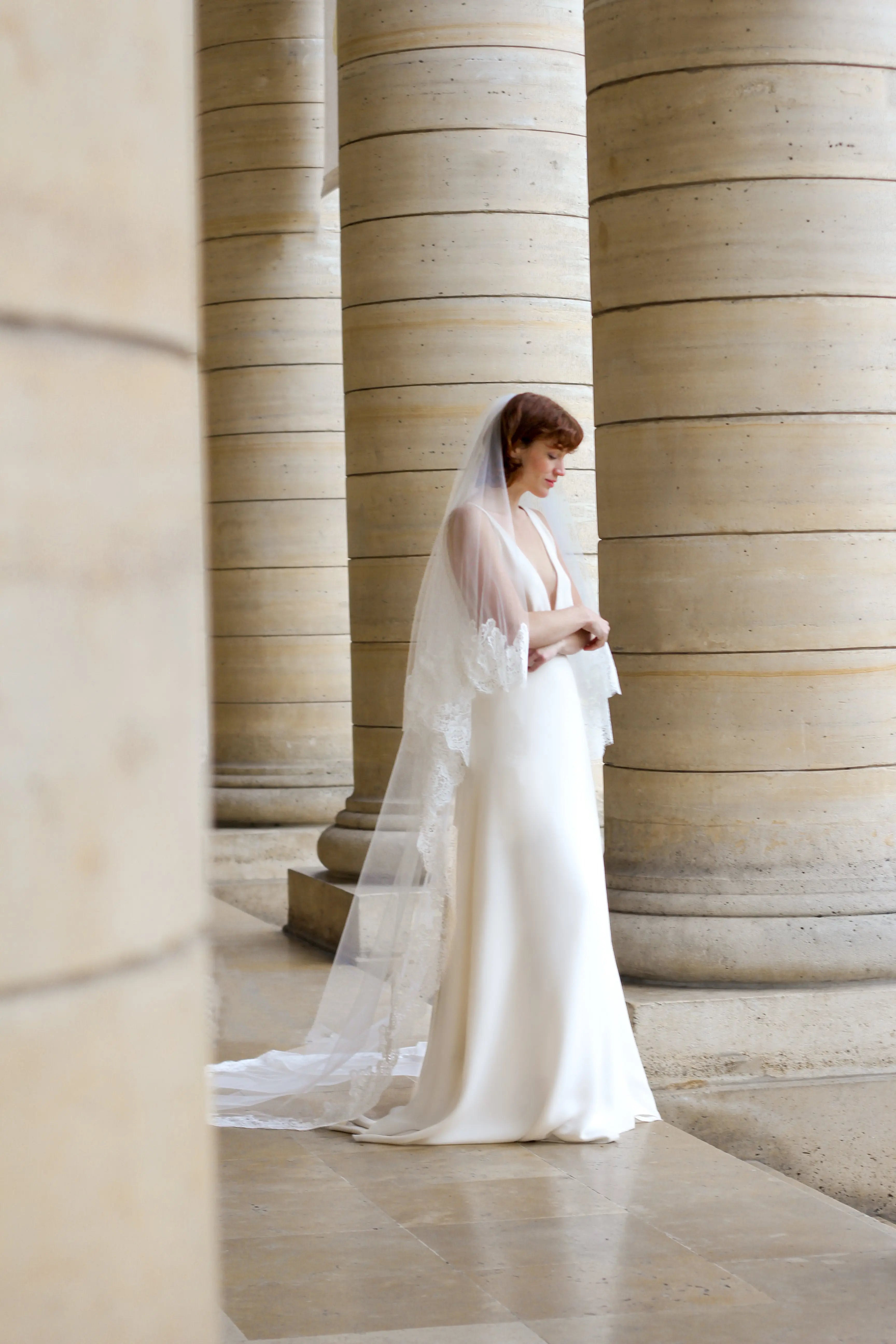 Young bride wearing a cathedral wedding veil with floral details on the edge.