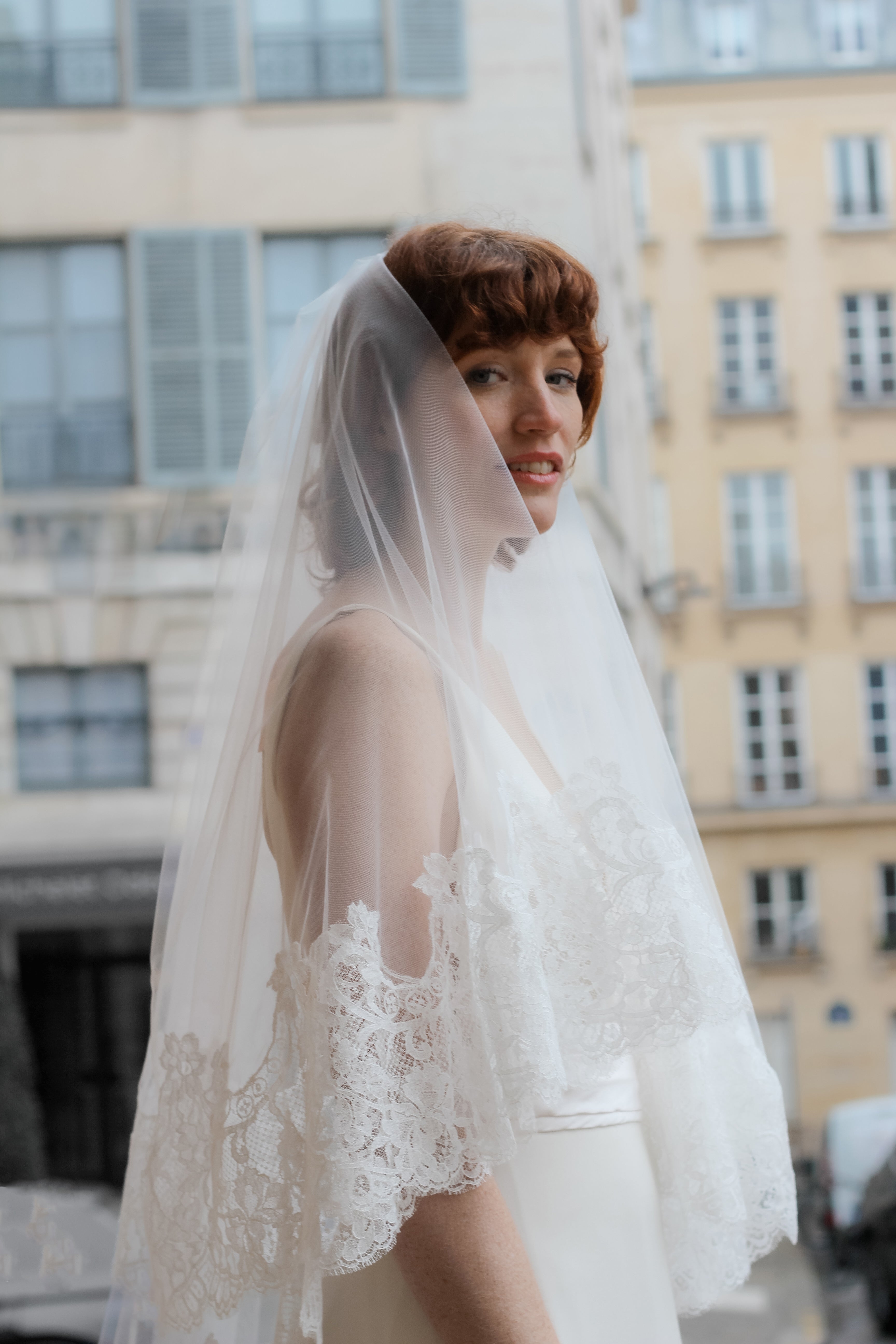 Young bride wearing a magnificent Calais lace wedding veil, looking straight at the camera.