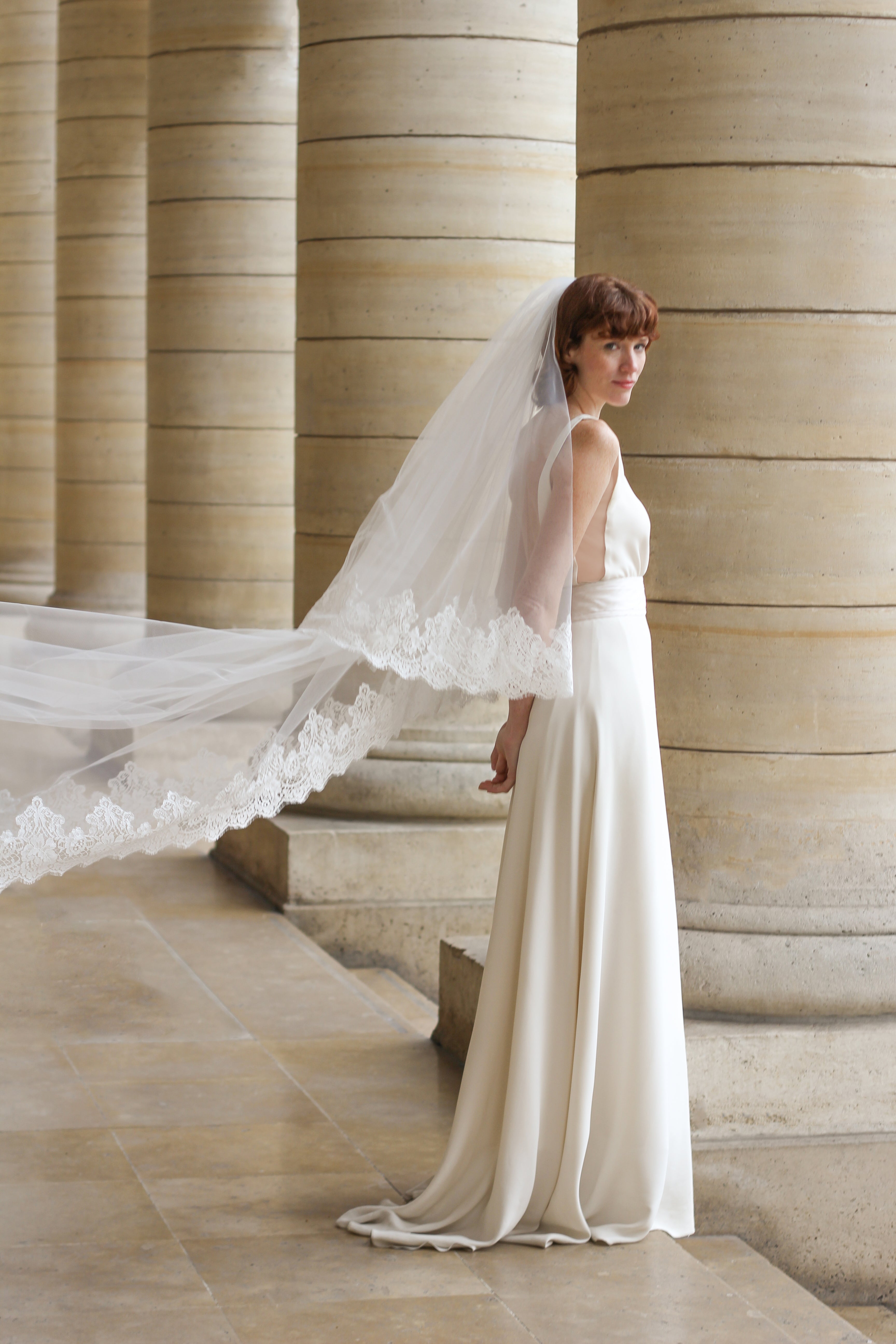 Young bride wearing a floral-edged wedding veil flowing in the wind.