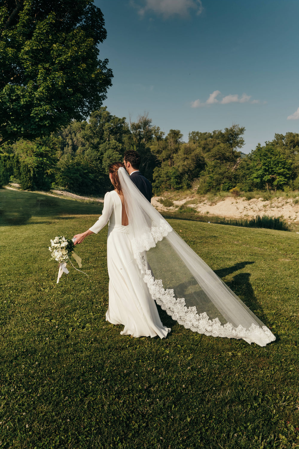 Bride wearing a lace wedding veil that is flowing in the wind