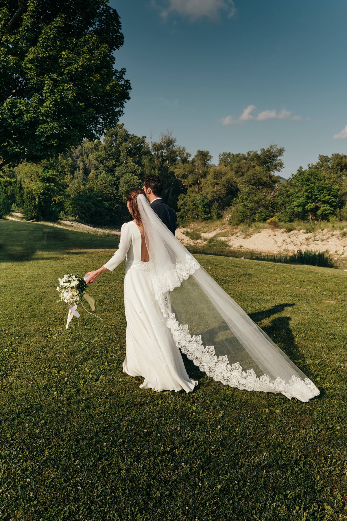 Bride wearing a lace wedding veil that is flowing in the wind
